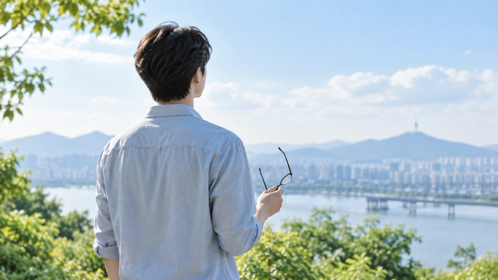 안경을 손에 들고 먼 풍경을 바라보는 20대